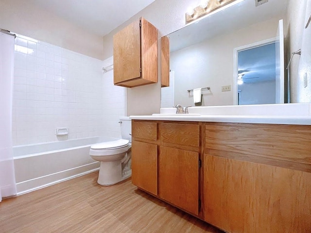 full bathroom featuring toilet, wood finished floors, vanity, a ceiling fan, and washtub / shower combination