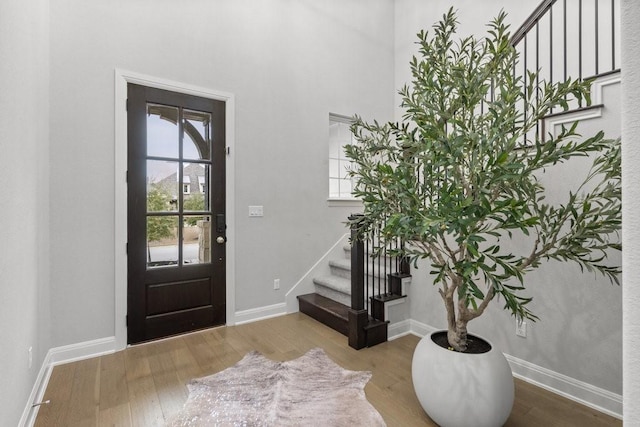 foyer entrance with stairway, wood finished floors, and baseboards