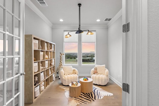 sitting room featuring visible vents, ornamental molding, light wood-style flooring, and baseboards