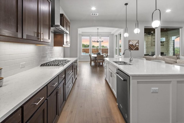 kitchen featuring a sink, visible vents, appliances with stainless steel finishes, wall chimney exhaust hood, and pendant lighting