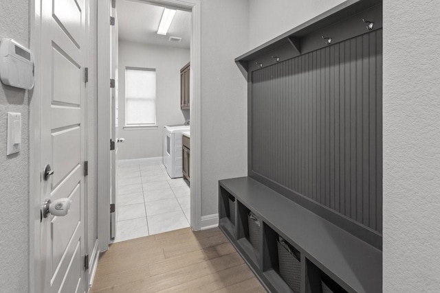 mudroom with light wood-type flooring, baseboards, and washing machine and clothes dryer