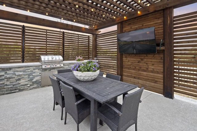 view of patio / terrace with outdoor dining area, an outdoor kitchen, a pergola, and area for grilling