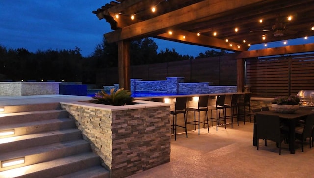 patio at twilight featuring a bar, ceiling fan, and area for grilling