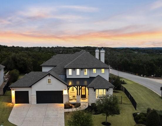 view of front of home featuring roof with shingles, a chimney, concrete driveway, a garage, and a front lawn