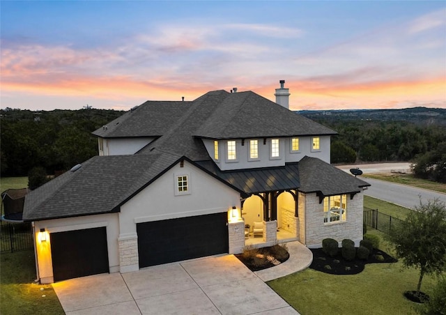 view of front of property with a shingled roof, fence, metal roof, stone siding, and driveway