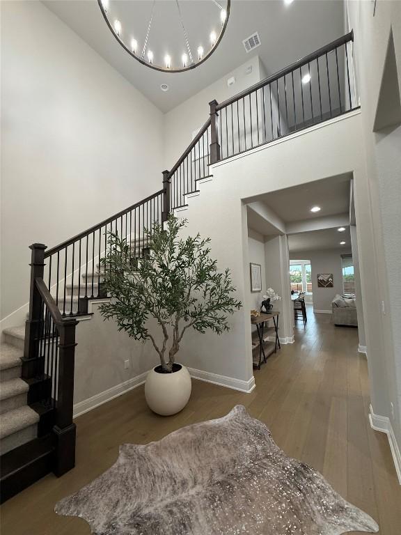 staircase with baseboards, a high ceiling, visible vents, and wood finished floors