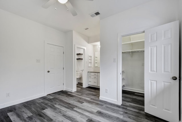 unfurnished bedroom featuring dark wood-style floors, baseboards, a spacious closet, and visible vents