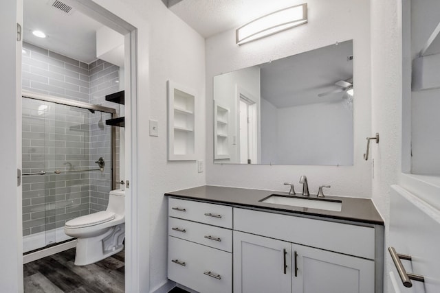 bathroom featuring a stall shower, visible vents, toilet, wood finished floors, and vanity