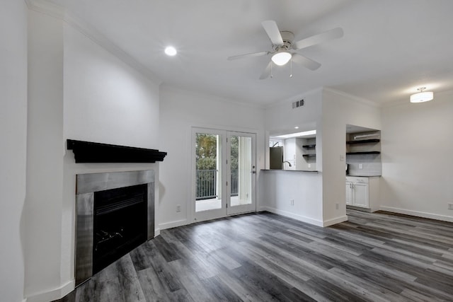 unfurnished living room with crown molding, a fireplace, baseboards, and dark wood-style flooring