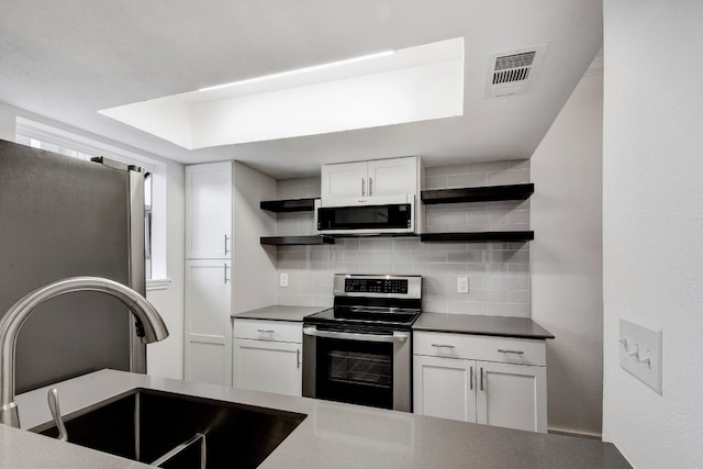 kitchen with stainless steel appliances, white cabinets, a sink, and open shelves