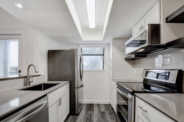 kitchen featuring stainless steel appliances, white cabinets, a sink, and backsplash