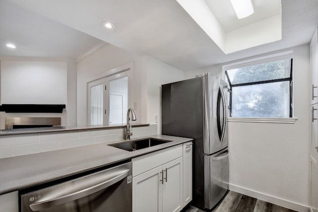 kitchen featuring baseboards, stainless steel appliances, light countertops, white cabinetry, and a sink