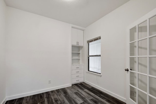 unfurnished room featuring dark wood-type flooring and baseboards