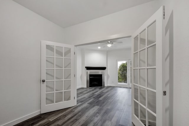 unfurnished living room featuring dark wood-style flooring, a fireplace, a ceiling fan, and baseboards