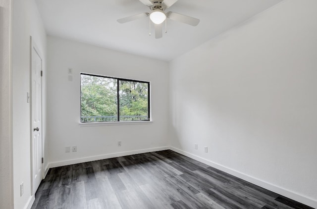 spare room with dark wood-style flooring, a ceiling fan, and baseboards