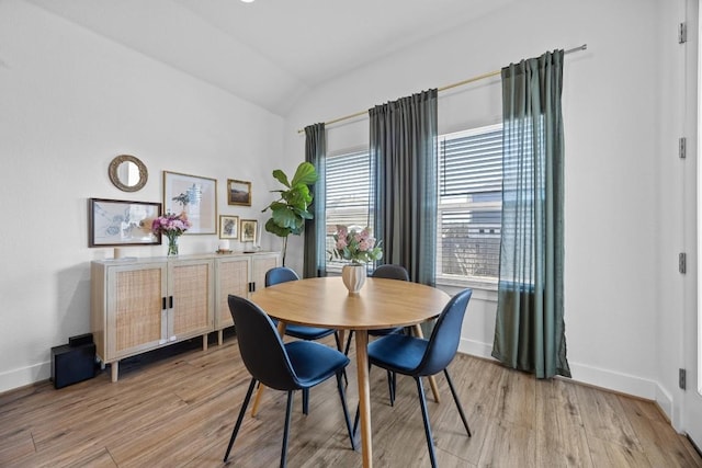 dining room with baseboards, vaulted ceiling, and light wood finished floors