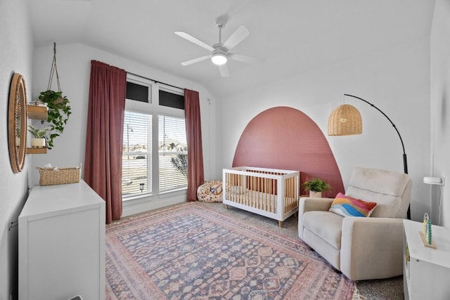 bedroom featuring lofted ceiling, a crib, and a ceiling fan