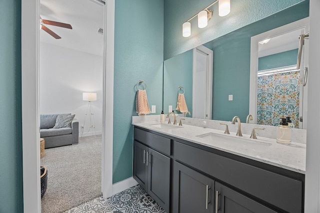 bathroom with ceiling fan, double vanity, a sink, and baseboards