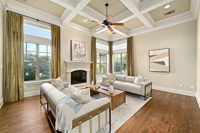 living area featuring beam ceiling, visible vents, a glass covered fireplace, wood finished floors, and baseboards