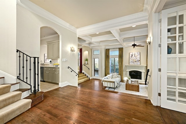 entryway featuring beam ceiling, a fireplace, stairway, wood finished floors, and coffered ceiling