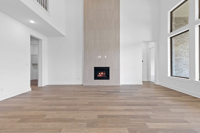 100 Wild Bluebell Cv, Georgetown, TX 78628 - unfurnished living room with a towering ceiling, a fireplace, and light wood finished floors