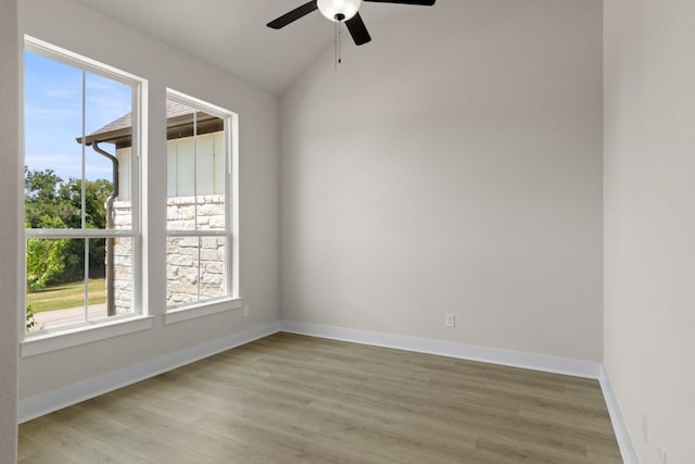 spare room featuring a wealth of natural light, vaulted ceiling, light wood-style flooring, and baseboards