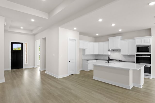 kitchen with tasteful backsplash, built in microwave, a sink, and light wood-style flooring