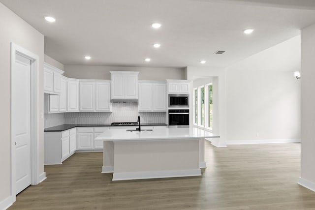 kitchen featuring tasteful backsplash, visible vents, stainless steel microwave, oven, and white cabinetry