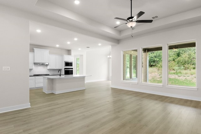 kitchen featuring visible vents, open floor plan, oven, built in microwave, and a tray ceiling