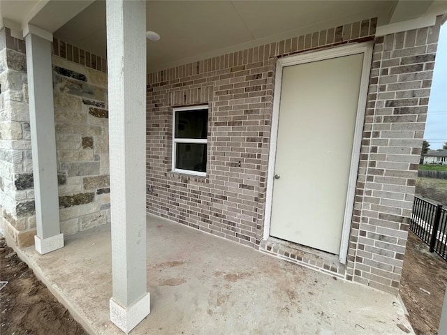 property entrance featuring a patio area and brick siding