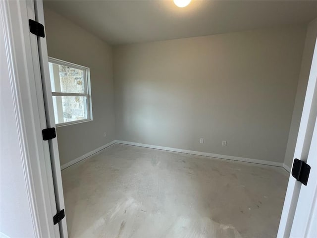 unfurnished room featuring baseboards and unfinished concrete flooring