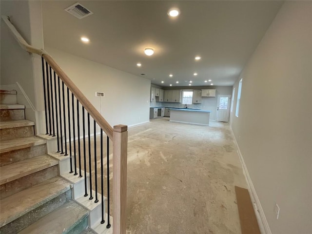 unfurnished living room with recessed lighting, visible vents, baseboards, stairs, and unfinished concrete floors