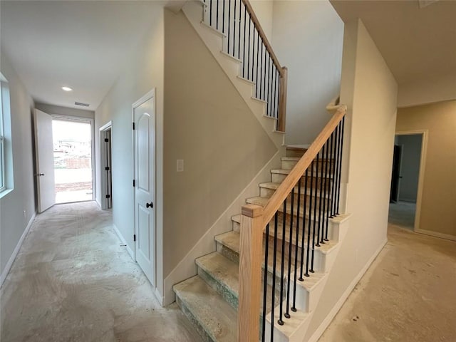 staircase with concrete flooring, visible vents, and baseboards