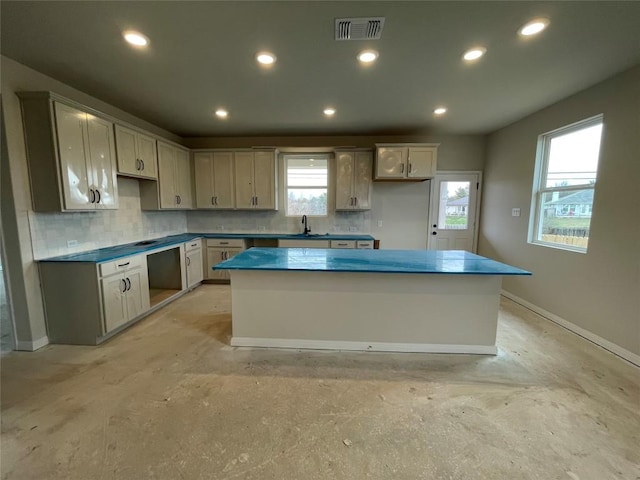 kitchen featuring dark countertops, tasteful backsplash, a kitchen island, and visible vents