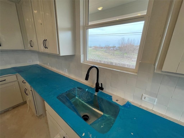 kitchen featuring dark countertops, tasteful backsplash, and a sink