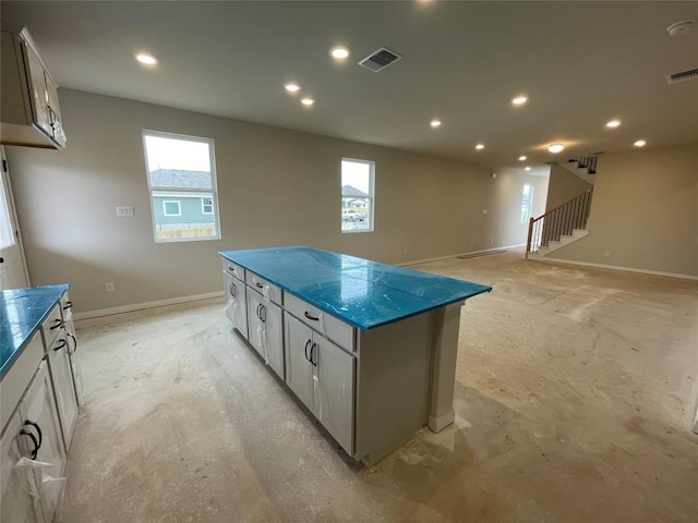 kitchen with plenty of natural light, visible vents, dark countertops, a center island, and white cabinetry