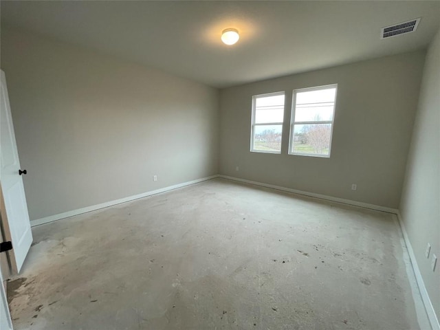 empty room with unfinished concrete floors, visible vents, and baseboards