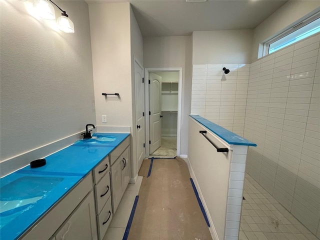 bathroom with double vanity, a walk in closet, a sink, and a walk in shower