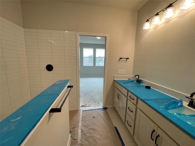 full bath featuring double vanity, tile patterned flooring, and a sink