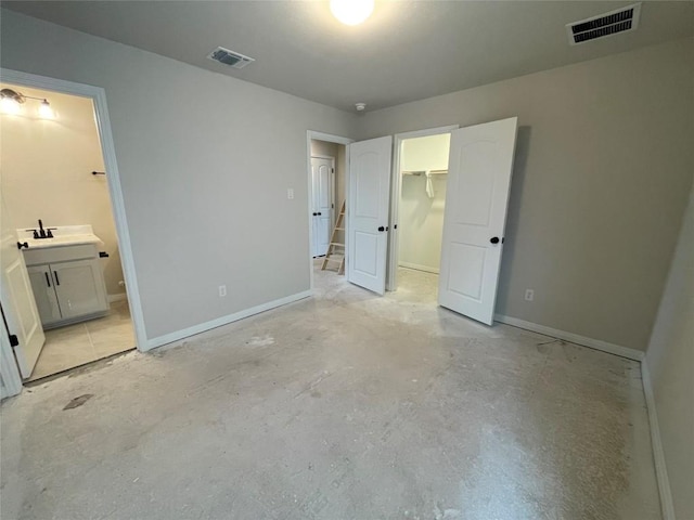 unfurnished bedroom featuring baseboards, a walk in closet, visible vents, and unfinished concrete floors