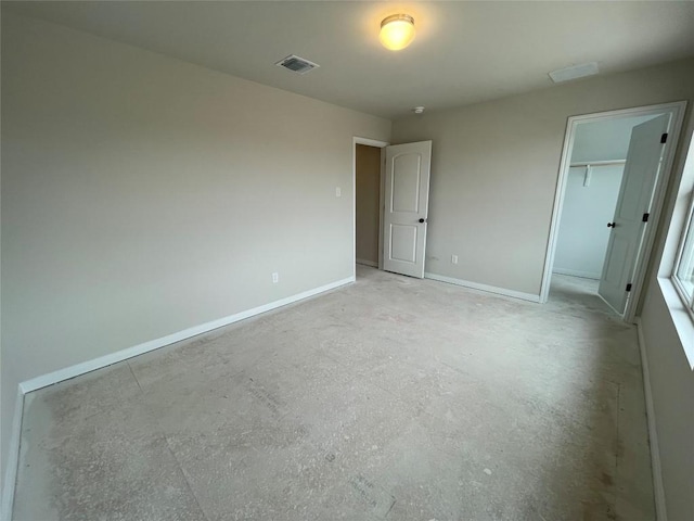 unfurnished bedroom with a closet, visible vents, concrete floors, and baseboards