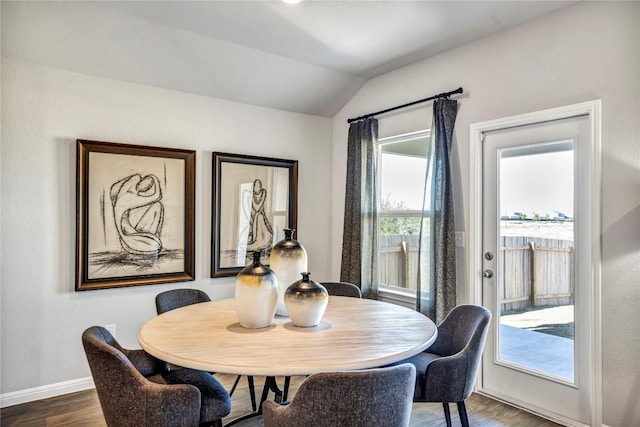 dining space with baseboards, vaulted ceiling, and wood finished floors