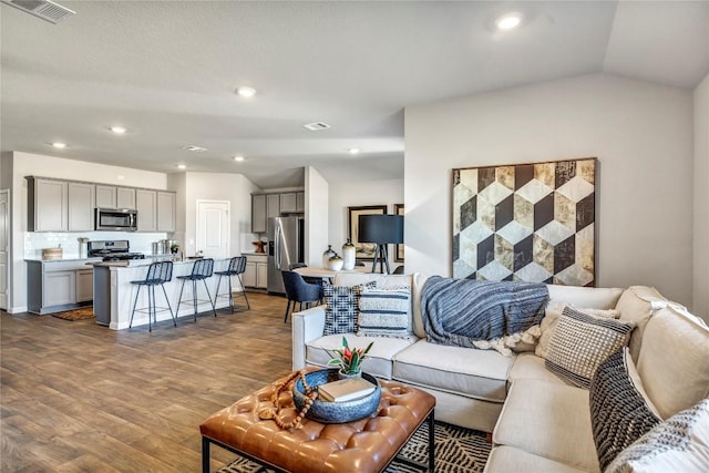 living room with visible vents, vaulted ceiling, wood finished floors, and recessed lighting