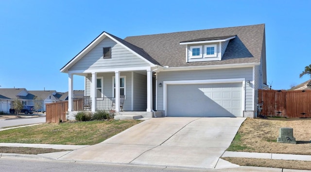 view of front of home with driveway, roof with shingles, an attached garage, covered porch, and fence