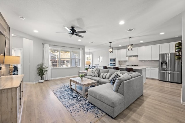 living room featuring visible vents, baseboards, a ceiling fan, light wood-style flooring, and recessed lighting