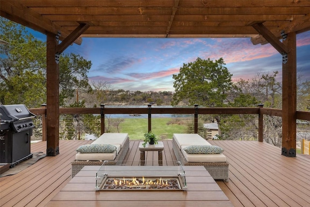 wooden terrace with an outdoor living space with a fire pit and area for grilling