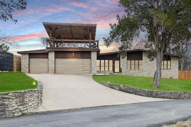 view of front of home featuring driveway, stone siding, and a front lawn