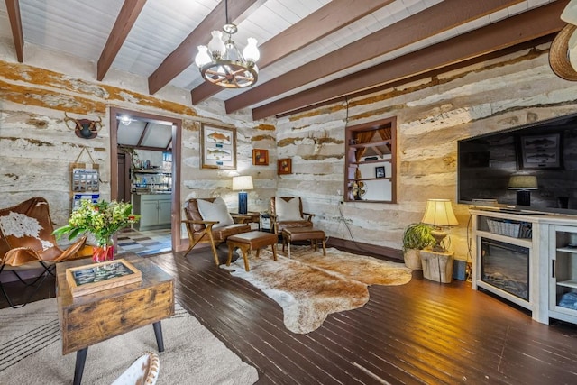 sitting room with a chandelier, dark wood-type flooring, beamed ceiling, and a glass covered fireplace