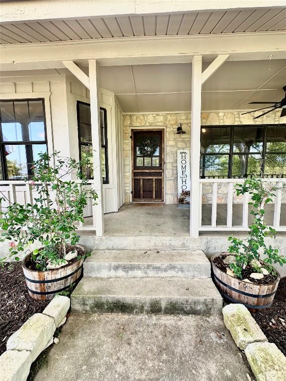 entrance to property with stone siding and a ceiling fan