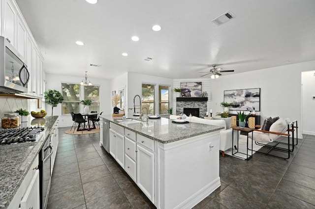 kitchen with appliances with stainless steel finishes, open floor plan, a kitchen island with sink, and white cabinetry